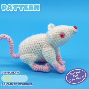 May include: Crochet pattern for a white amigurumi rat with pink ears, paws, and tail. The pattern is labeled "Advanced Beginner" and includes an "Instant PDF Download" button.