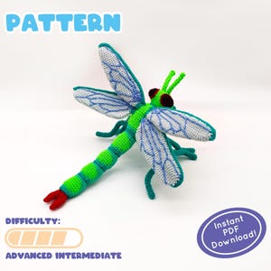 以下が含まれることがあります： 緑、青、白の羽を持つかぎ針編みのトンボのパターン。 トンボは、青いアクセントと赤い先端を持つ緑色の体を持っています。 「PATTERN」という単語は青いテキストです。 難易度は「上級中級」です。