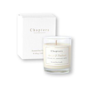 Puede incluir: Vela perfumada de soja en un vaso transparente con una etiqueta blanca, junto con una caja blanca. La vela está etiquetada como "Chapters Amber & Patchouli". La caja tiene la palabra "Chapters" impresa. Peso: 165 g.