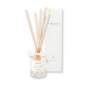 May include: A glass reed diffuser with wooden reeds and a white ribbon. The label reads "Chapters Sweet Fig & Coconut". A white box with the "Chapters" logo is behind the diffuser. The product is designed for home fragrance.