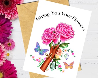 May include: A greeting card with the text "Giving You Your Flowers" in black lettering. The card features a hand holding a bouquet of pink peonies with green leaves and two butterflies, one blue and one orange.
