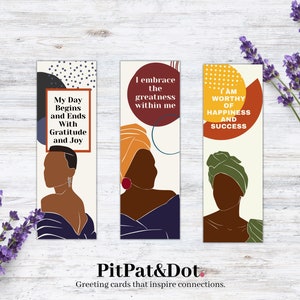 May include: Three colorful bookmarks with inspirational quotes and abstract illustrations of women with head wraps. The quotes are "My Day Begins and Ends With Gratitude and Joy", "I embrace the greatness within me", and "I am worthy of happiness and success".