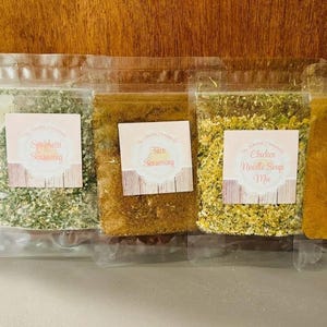 Puede incluir: Cinco bolsas de plástico transparente llenas de varias especias. Cada bolsa tiene una etiqueta con texto, incluyendo "Chili Mix Seasoning", "Spaghetti Seasoning", "Taco Seasoning", "Chicken Noodle Soup Mix" y "Pumpkin Pie Spice."