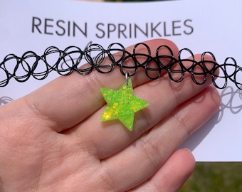 May include: A black choker necklace with a green star-shaped charm. The star is made of resin and has glitter embedded in it. The text "RESIN SPRINKLES" is visible in the background.