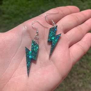 May include: A pair of silver earrings with green glitter lightning bolt charms.