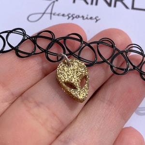 Può includere: Collana choker nera con ciondolo alieno in glitter dorato. Il choker è realizzato in elastico e ha una vestibilità elastica.