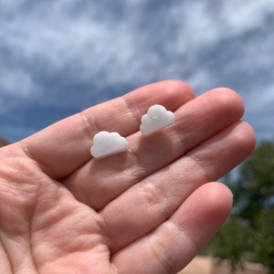May include: A pair of white cloud-shaped earrings with a subtle sparkle.