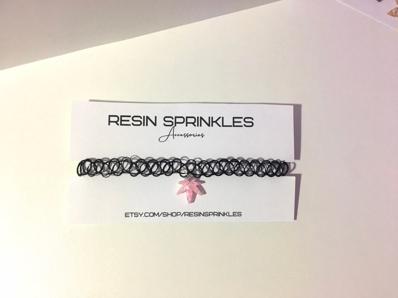 Op de afbeelding: Zwarte choker ketting met een roze hars blad hanger. De hanger is ingelegd met glitter. De ketting wordt getoond op een witte kaart met de tekst "RESIN SPRINKLES Accessories" en "ETSY.COM/SHOP/RESINSPRINKLES".