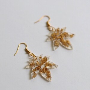 May include: A pair of gold leaf earrings with a clear resin leaf design.