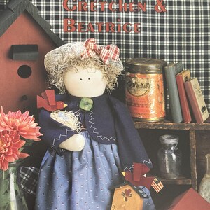 May include: A book cover featuring a handmade doll with a blue dress and red and white gingham bow. The doll is holding a birdhouse and is surrounded by other birdhouses, a flower, and a jar. The title of the book is "Gretchen & Beatrice" and the text "Converted by Betty Mygran" is at the bottom of the cover.