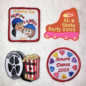 May include: Four embroidered patches with various themes. The first patch is red and white with the text "Thinking Day 2005" and depicts two girls with flags. The second patch is orange and pink with the text "SU 8 Skate Party 2003". The third patch is white with a black and white film reel and a red and white popcorn bucket with the text "Girls Night at the Movies 2004". The fourth patch is white with a red border and the text "Amore Dance 2003" surrounded by colorful hearts.