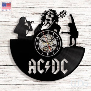 Könnte beinhalten: Schwarze Schallplattenuhr mit einer Silhouette einer Rockband, die Musik spielt. Das Zifferblatt der Uhr ist weiß mit schwarzen Zahlen und einem silbernen AC/DC-Logo.