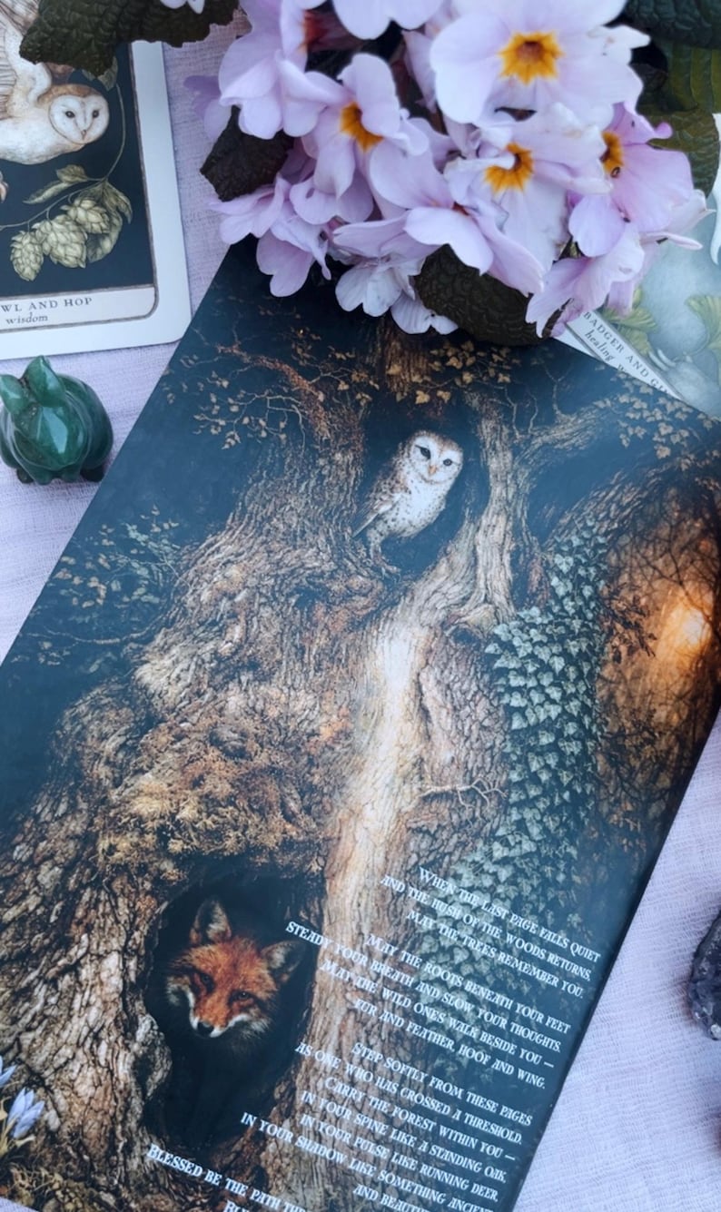 May include: An illustrated card featuring a detailed drawing of a tree with an owl in a hollow and a fox in another. The card has text on it and is surrounded by pink flowers and other cards.