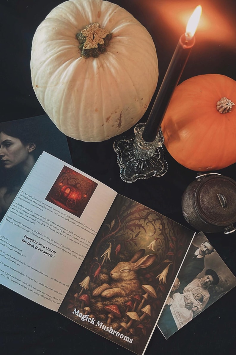May include: A still-life arrangement featuring a white pumpkin, an orange pumpkin, a lit black candle in a glass holder, and an open book with the text "Magick Mushrooms". Other items include a small cauldron and vintage photographs.