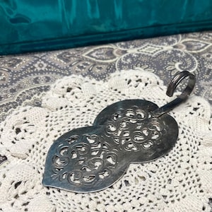 May include: A handmade wooden sign with the text "Welcome" in a whimsical font. The sign is painted white with a distressed finish, and features a decorative floral design in shades of pink and green. It measures approximately 12 inches wide.