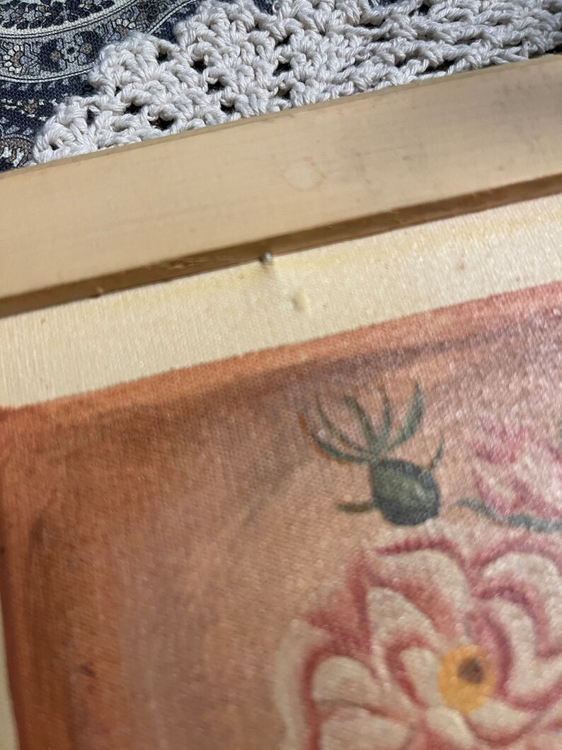 Puede incluir: Primer plano de una pintura enmarcada de una rosa rosa con un insecto verde en el tallo. La pintura est&aacute; sobre lienzo con un fondo marr&oacute;n.