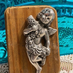 Vintage silver tone metal cherub on wood plague