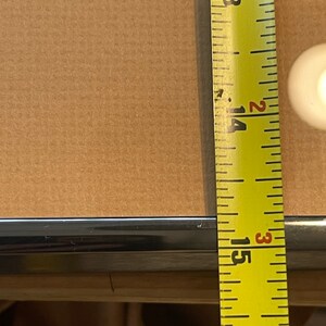 May include: Close-up of a yellow measuring tape with black markings. The tape is extended to 15 3/8 inches.