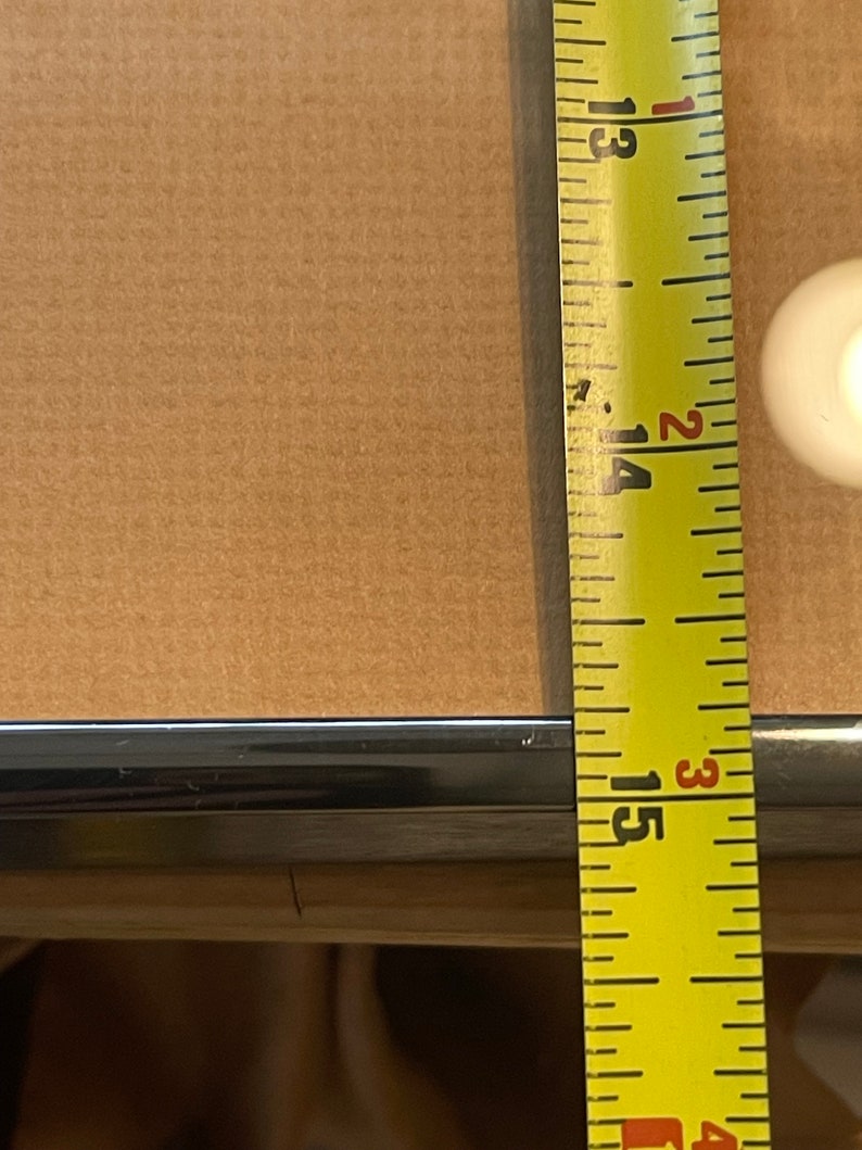 May include: Close-up of a yellow measuring tape with black markings. The tape is extended to 15 3/8 inches.