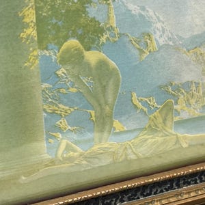 May include: A vintage framed print of a painting depicting two nude figures in a landscape setting. The figures are in a soft, muted color palette of green, blue, and yellow. The print is framed in a gold-colored frame with a black and gold patterned border.