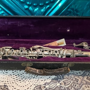 Antique or vintage clearly aged clarinet possible silver plated marked 6925 with Paris made mouthpiece in worn purple lined case