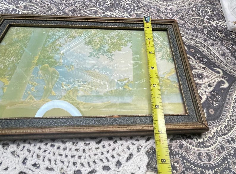 May include: A vintage framed picture with a light blue and green landscape scene. The frame is made of wood with a dark brown finish and a decorative gold trim.