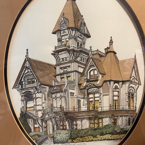 May include: A black and white pen and ink drawing of a Victorian mansion with a tower. The drawing is framed in a brown oval frame with a black border. The text "Carson Mansion, Eureka, California" is written below the drawing.