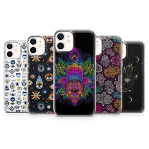 Op de afbeelding: Vijf verschillende iPhone-hoesjes met verschillende ontwerpen met het boze oog en het Hamsa-handsymbool. De ontwerpen omvatten een witte achtergrond met blauwe boze ogen, een zwarte achtergrond met gouden boze ogen, een zwarte achtergrond met een regenboog Hamsa-hand, een paarse achtergrond met zilveren Hamsa-handen en een zwarte achtergrond met een gouden Hamsa-hand en sterren.
