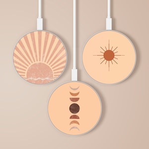 Puede incluir: Tres cargadores inalámbricos redondos con diseños bohemios. Uno presenta un amanecer, otro un sol con rayos y el tercero fases lunares. Cada cargador tiene un cable blanco y una paleta de colores neutros.