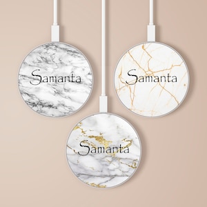 Puede incluir: Tres cargadores inalámbricos redondos con diferentes patrones de mármol. Los cargadores son blancos con patrones de mármol negro, dorado y blanco y dorado. Cada cargador tiene el nombre "Samanta" escrito en él.