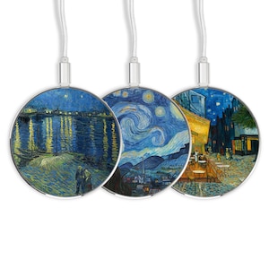 Puede incluir: Tres almohadillas de carga inalámbrica redondas con diferentes imágenes de las pinturas de La Noche Estrellada de Vincent van Gogh. Las almohadillas de carga son plateadas con un cable blanco.