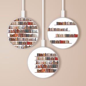 Puede incluir: Tres marcos redondos blancos con cordones negros que cuelgan del techo. Cada marco contiene una estantería llena de libros. Los libros están dispuestos en filas en los estantes. Los libros son principalmente marrones y negros con algunas lomo rojas.