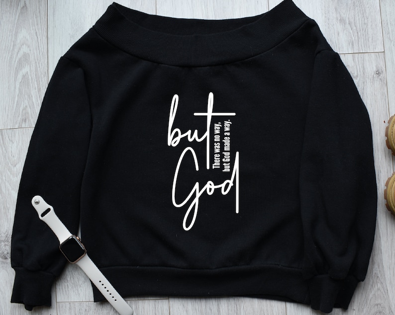 May include: Black off-the-shoulder sweatshirt with the text "but God" in white. The text is accompanied by the phrase "There was no way, but God made a way."