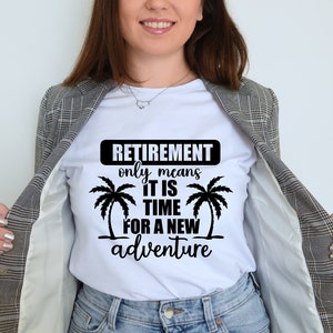 May include: White t-shirt with black text that reads "Retirement only means it is time for a new adventure". Two palm trees are on either side of the text. A woman is wearing the t-shirt and a gray blazer.