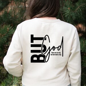May include: A white long-sleeved shirt with black text that reads "But God" and "There was no way, but God made a way."