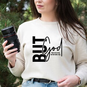 May include: A white sweatshirt with black text that reads "But God" and the phrase "There was no way, but God made a way."