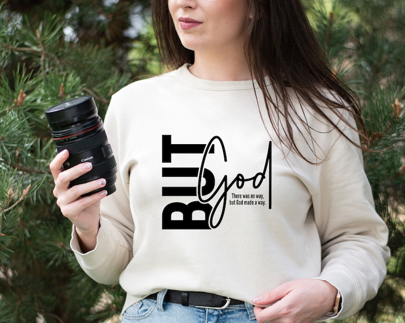 May include: A white sweatshirt with black text that reads "But God" and the phrase "There was no way, but God made a way."