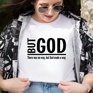 May include: White t-shirt with black text that reads "BUT GOD There was no way, but God made a way."