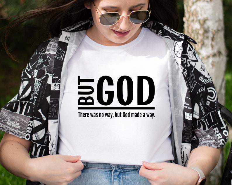 May include: White t-shirt with black text that reads "BUT GOD There was no way, but God made a way."