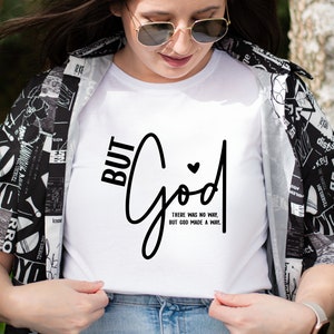 May include: White t-shirt with black text that reads "BUT GOD" in a cursive font. The text "THERE WAS NO WAY, BUT GOD MADE A WAY." is written in a smaller font below the main text.