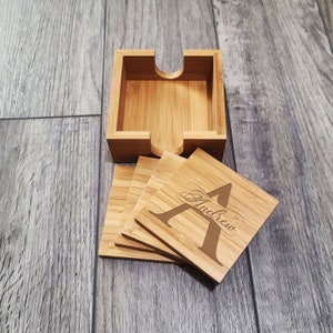 May include: Set of six bamboo coasters with a holder. The coasters are engraved with the letter "A" and the name "Andrew".