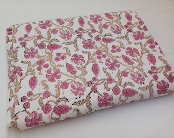May include: White cotton fabric with a pink and brown floral print. The fabric is folded in half and has a smooth texture.