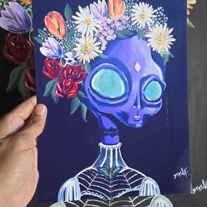 Può includere: Dipinto di un alieno viola con grandi occhi azzurri, adornato da una corona floreale di margherite, tulipani e rose. L'alieno ha una gemma a forma di diamante sulla fronte e un disegno a ragnatela sul petto.