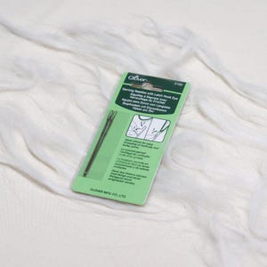 May include: A green and white packet of Clover brand darning needles with latch hook eyes. The packet includes a description of the needles in English, French, German, Spanish, and Italian. The needles are designed for easy threading of bulky yarns and crochet.