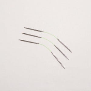 May include: Four silver knitting needles with green cords attached to the ends. The needles are arranged in a fan shape.