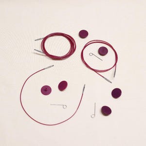 May include: A set of interchangeable circular knitting needles with burgundy cables and tips. The set includes four burgundy cable lengths, four burgundy tips, and two metal joiners.