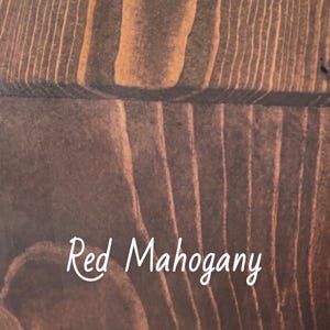 May include: Close-up of a wooden surface with a rich, reddish-brown hue. The wood grain is prominently displayed, with the text "Red Mahogany" in a cursive font. The wood has a warm, inviting appearance.
