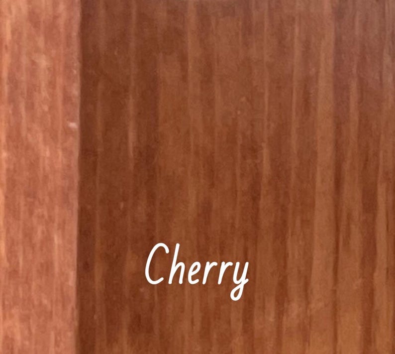 May include: A white ceramic mug with a black handle and the text "But First, Coffee" in a bold, black font. The mug is on a wooden surface. The mug is approximately 10 cm tall.