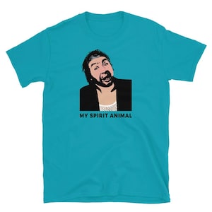 May include: A bright turquoise short-sleeve t-shirt featuring a graphic illustration of a man with dark hair and a beard wearing a black jacket over a white mesh top. Below the illustration, the text reads MY SPIRIT ANIMAL in black letters.