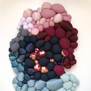 May include: Abstract wall art composed of fabric bubbles in a gradient of colors. The piece transitions from light blue to dark blue, then to black, burgundy, and finally, pink. Some bubbles have copper-colored accents.
